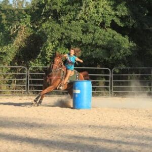 Horse and rider rounding blue barrel